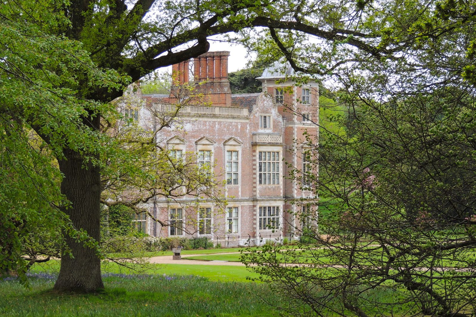 Grand Elizabethan manor house framed by mature parkland trees